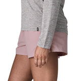 Side of woman wearing Patagonia's quick drying women's barely baggies shorts in light pink, shorts have a loose fit