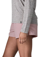 Side of woman wearing Patagonia's quick drying women's barely baggies shorts in light pink, shorts have a loose fit