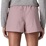 Back of woman wearing Patagonia's quick drying women's barely baggies shorts in light pink. Shorts have a loose fit