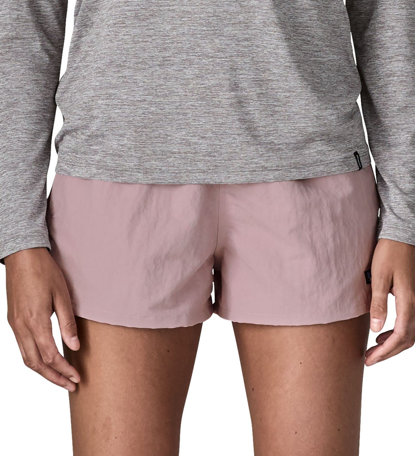 Front of woman wearing Patagonia'squick drying women's barely baggies shorts in light pink. Shorts have a loose fit