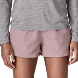 Front of woman wearing Patagonia'squick drying women's barely baggies shorts in light pink. Shorts have a loose fit