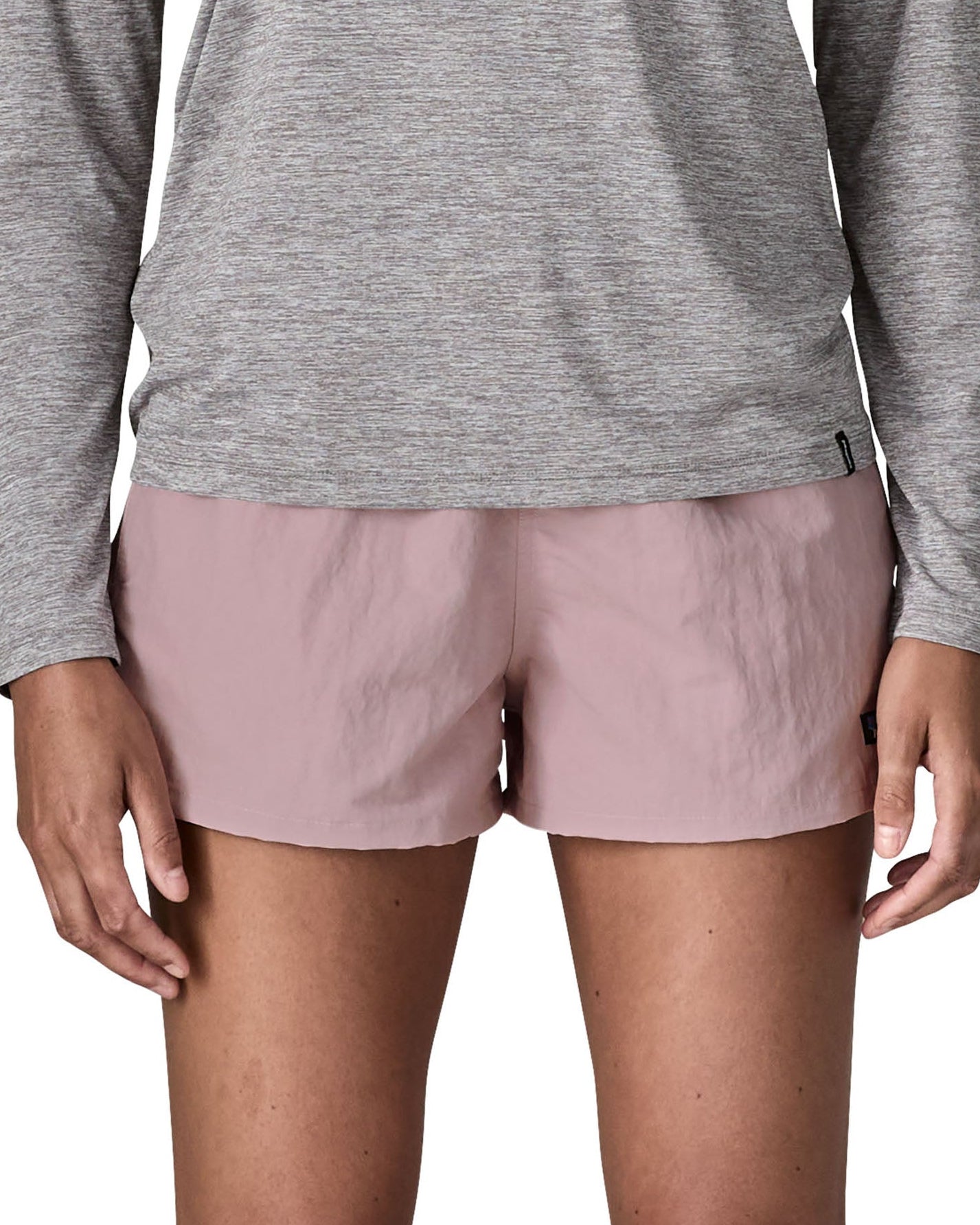 Front of woman wearing Patagonia'squick drying women's barely baggies shorts in light pink. Shorts have a loose fit