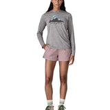 Woman wearing Patagonia's quick drying women's barely baggies shorts in light pink with hand in side pocket. 
