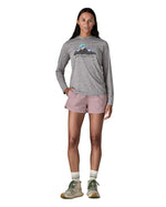 Woman wearing Patagonia's quick drying women's barely baggies shorts in light pink with hand in side pocket. 