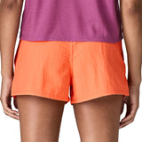 Back of woman wearing Patagonia's quick drying women's barely baggies shorts in bright orange. Shorts have a loose fit