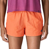 Front of woman wearing Patagonia's quick drying women's barely baggies shorts in bright orange. Shorts have a loose fit
