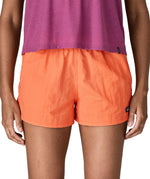 Front of woman wearing Patagonia's quick drying women's barely baggies shorts in bright orange. Shorts have a loose fit