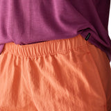 Woman wearing Patagonia's quick drying women's barely baggies shorts in bright orange showing elasticated waist band