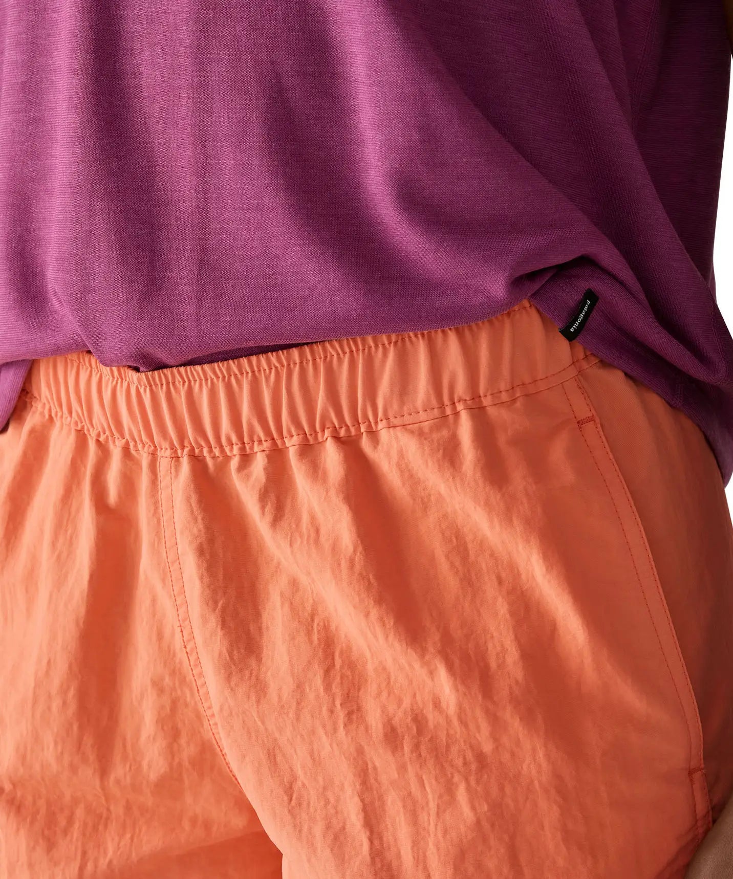 Woman wearing Patagonia's quick drying women's barely baggies shorts in bright orange showing elasticated waist band