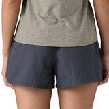 Back of woman wearing Patagonia's quick drying women's barely baggies shorts in navy blue. Shorts have a loose fit