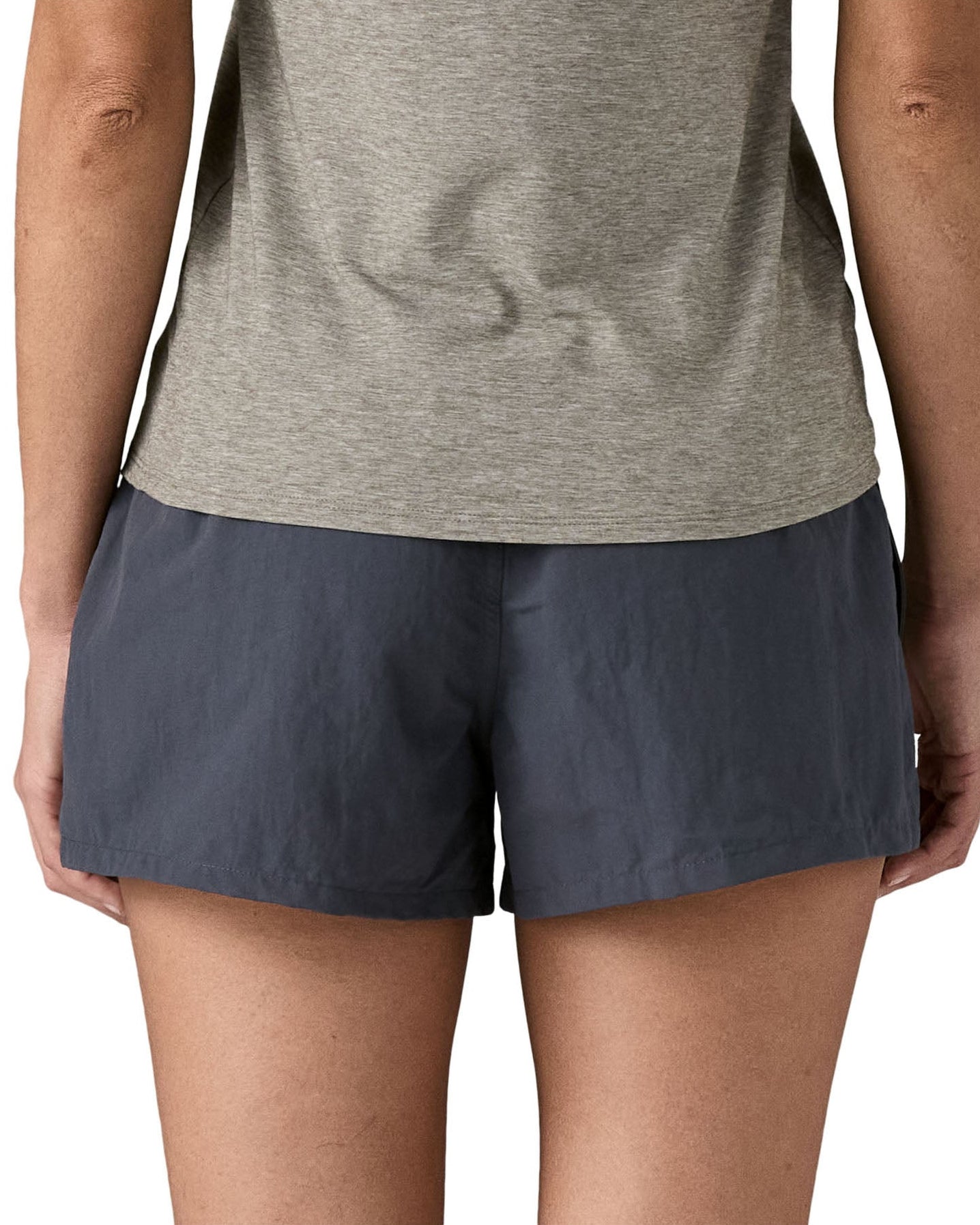 Back of woman wearing Patagonia's quick drying women's barely baggies shorts in navy blue. Shorts have a loose fit