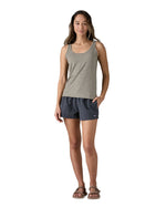 Woman wearing Patagonia's quick drying women's barely baggies shorts in navy blue with hand in side pocket. 