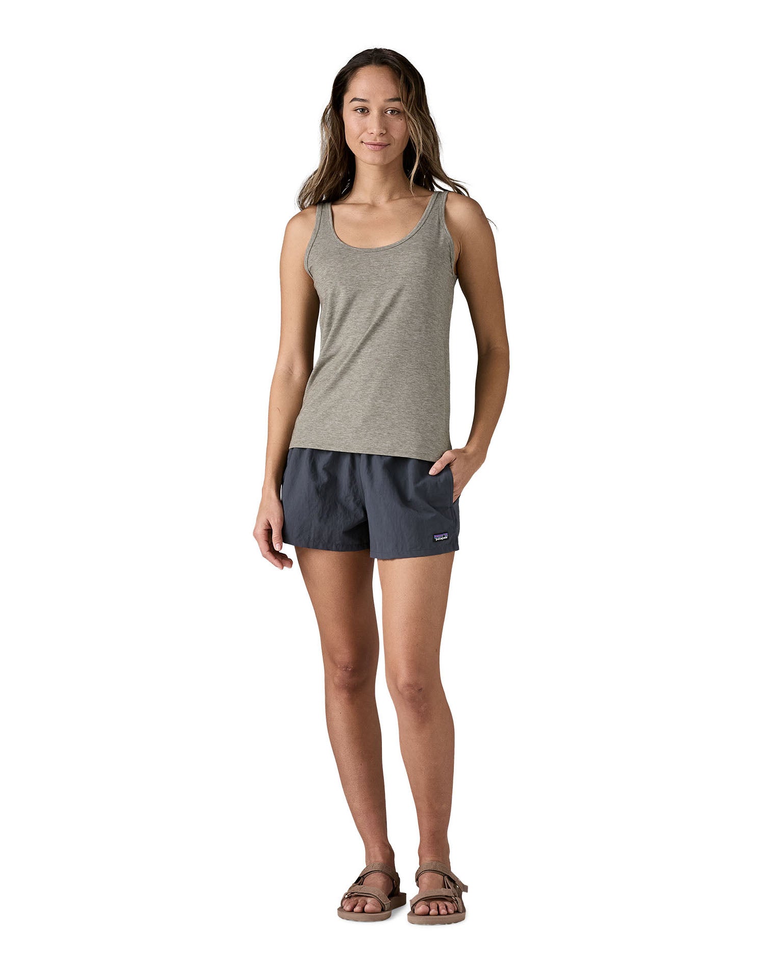 Woman wearing Patagonia's quick drying women's barely baggies shorts in navy blue with hand in side pocket. 
