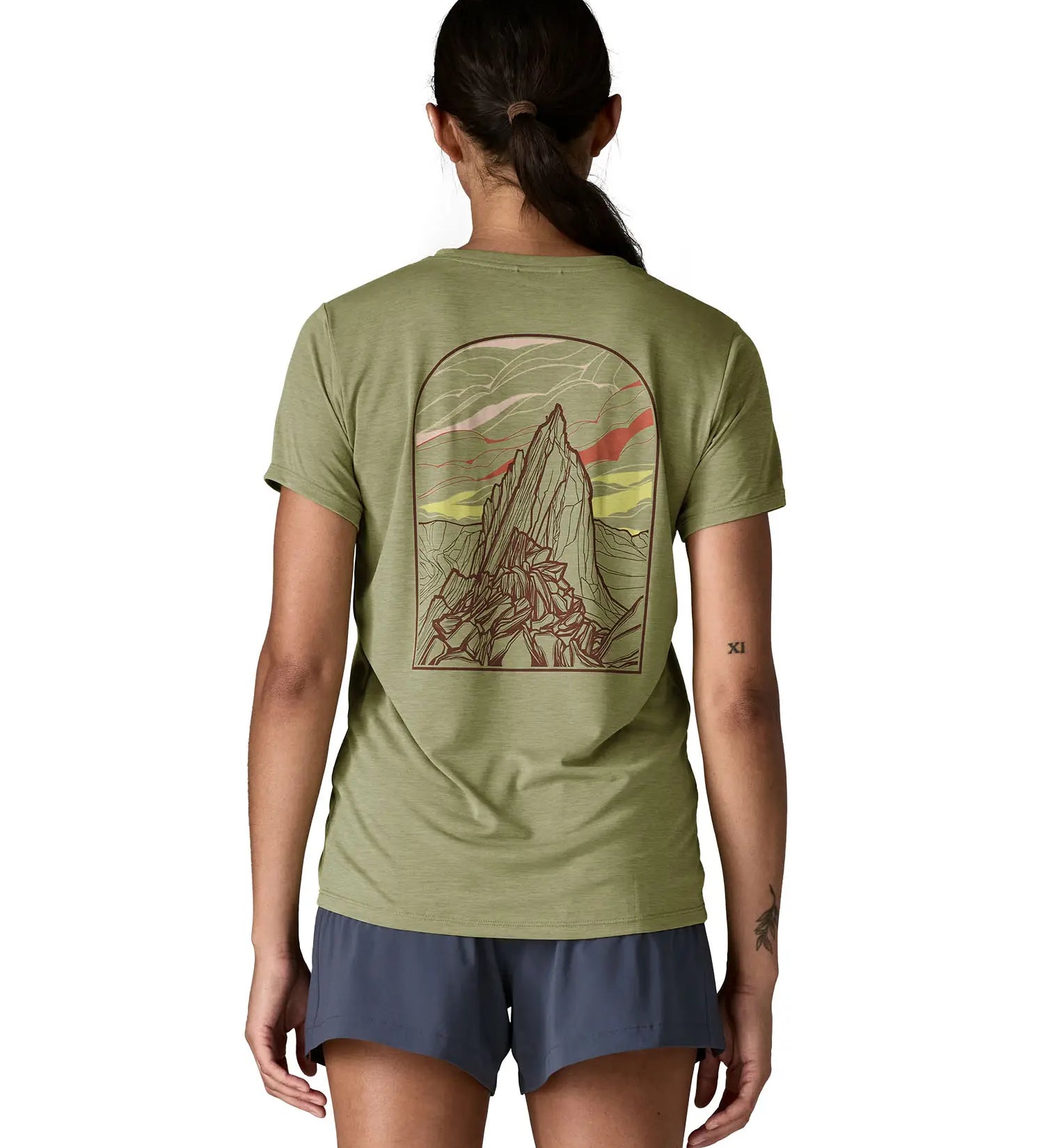 Woman wearing Patagonia women's capilene cool daily short sleeve t-shirt in green showing large mountain graphic on the back