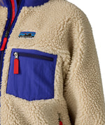 A close up of the A Patagonia women's classic retro-x jacket in a dark natural colour way available at Babipur showing the royal blue zipped chest pocket detail