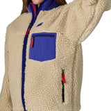 An image of a women wearing the Patagonia women's classic retro-x jacket in a dark natural colour way available at Babipur showing the royal blue trim detail