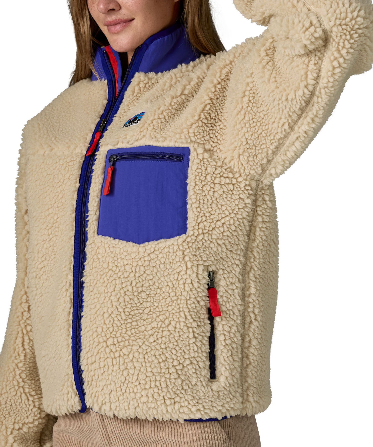 An image of a women wearing the Patagonia women's classic retro-x jacket in a dark natural colour way available at Babipur showing the royal blue trim detail