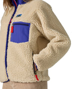 An image of a women wearing the Patagonia women's classic retro-x jacket in a dark natural colour way available at Babipur showing the thick fleece detail