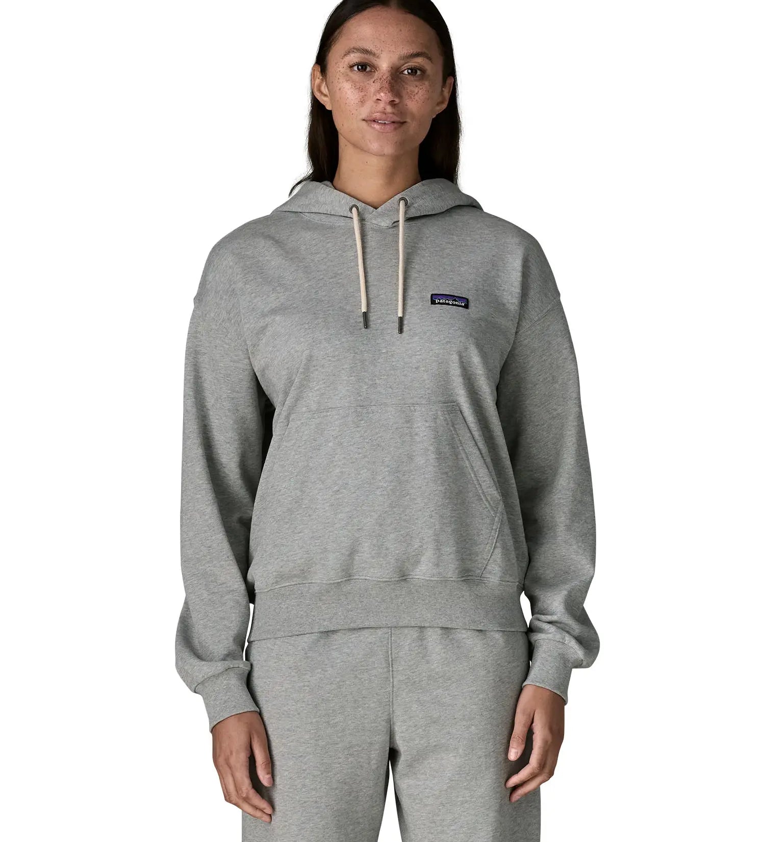 Woman wearing Patagonia's daily hoody in grey showing the kangaroo pouch pocket. Hoody has a relaxed fit and sits around the hips