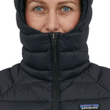 A person wearing the Patagonia Women's Down Sweater Hoody, showing how the zip goes past the chin to keep the face warm