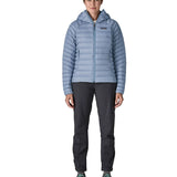 Front of Woman wearing the Patagonia down insulated sweater hoody in barnacle blue. Jacket has a relaxed fit and sits around the hips