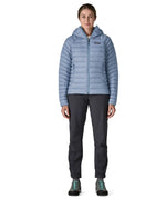 Front of Woman wearing the Patagonia down insulated sweater hoody in barnacle blue. Jacket has a relaxed fit and sits around the hips