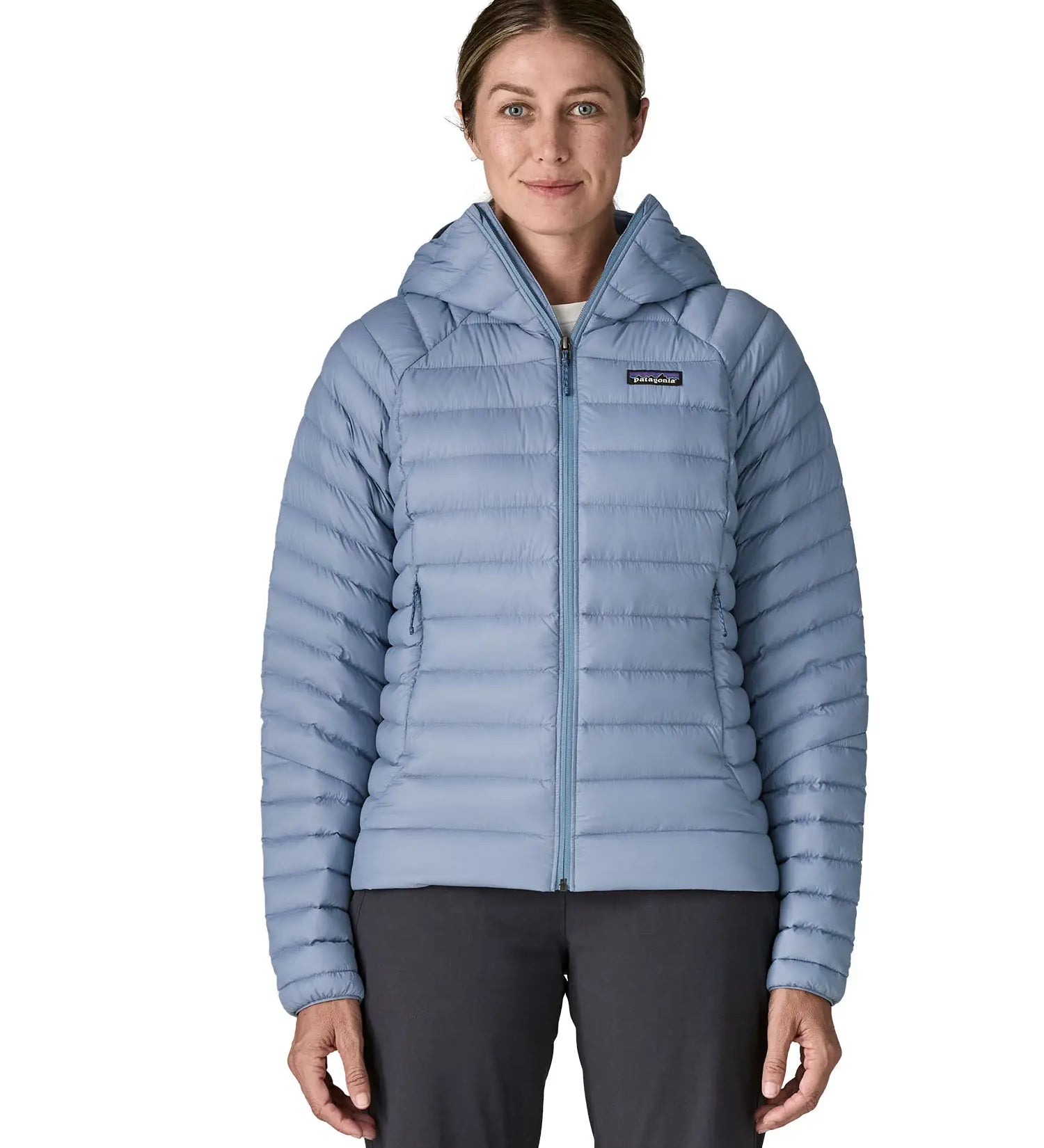 Woman wearing the Patagonia down insulated sweater hoody in barnacle blue fully zipped. Jacket has a regular fit