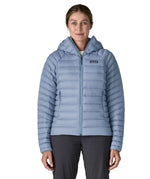 Woman wearing the Patagonia down insulated sweater hoody in barnacle blue fully zipped. Jacket has a regular fit