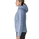 Side of Woman wearing the Patagonia down insulated sweater hoody in barnacle blue. Jacket has a relaxed fit and sits around the hips