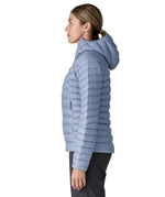 Side of Woman wearing the Patagonia down insulated sweater hoody in barnacle blue. Jacket has a relaxed fit and sits around the hips