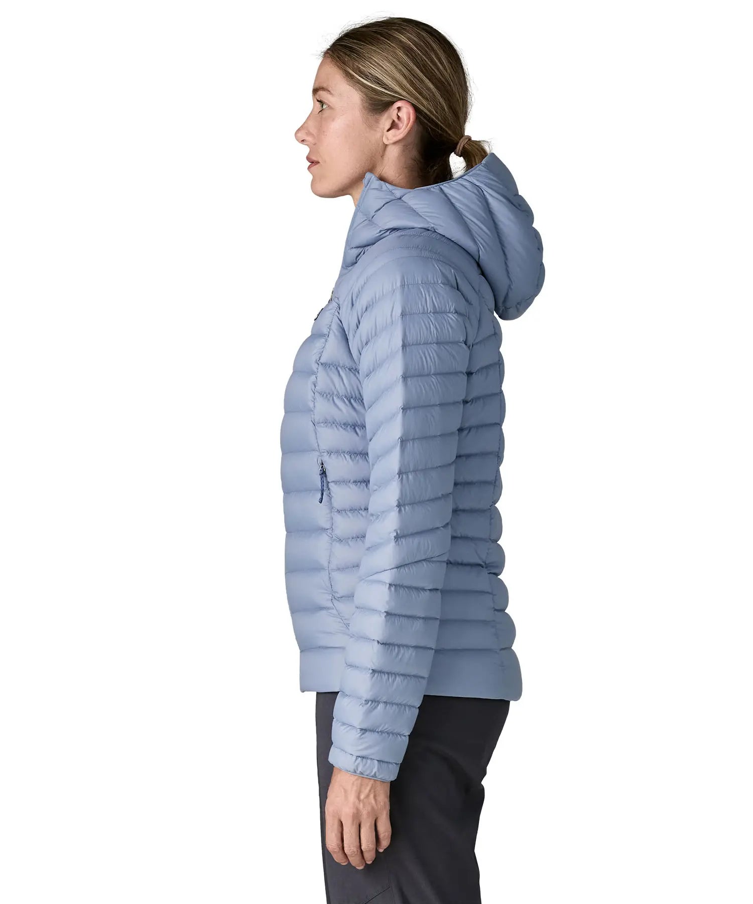 Side of Woman wearing the Patagonia down insulated sweater hoody in barnacle blue. Jacket has a relaxed fit and sits around the hips