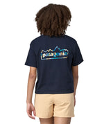 Back of Woman wearing Patagonia women's unity Fitz roy responsibili short sleeve tshirt in navy blue.