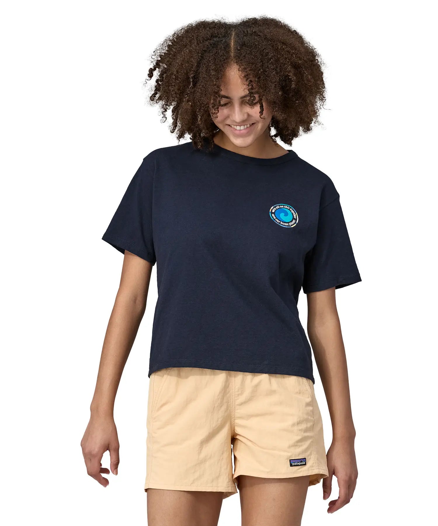 Woman wearing Patagonia women's unity Fitz roy responsibili short sleeve tshirt in navy  blue. Top has a boxy fit