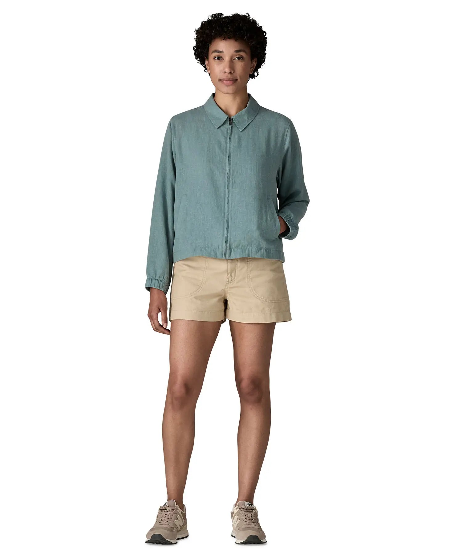 Woman wearing Patagonia women's lightweight jacket in blue. Features a full length front zip and side pockets. Jacket has a boxy fit and sits at the hips