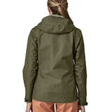 The back of the Patagonia Women's Torrentshell 3L Rain Jacket - Pine Needle Green. The image shows a person wearing the jacket to show the fit of the coat from the back and the hood