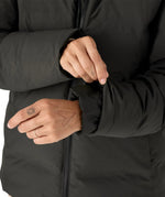 Woman pulling on the cuff on the Patagonia's waterproof Jackson glacier jacket in black showing the inner lining