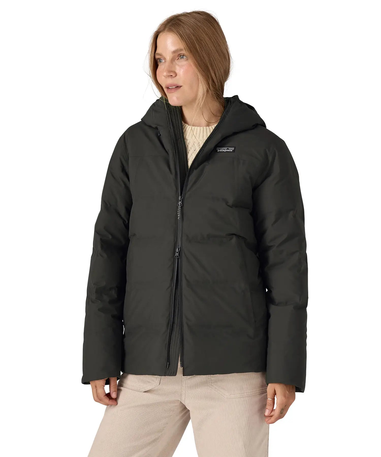 Woman wearing Patagonia's waterproof Jackson glacier hooded jacket in black showing front double zips opening the jacket