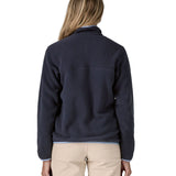 Back of a woman wearing Patagonia's synchilla snap t fleece in dark blue. Fleece has a relaxed fit and sits around the hips