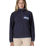 Woman wearing Patagonia's synchilla snap t fleece in dark blue. Fleece has a relaxed fit and sits around the hips