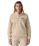 A woman wearing the Patagonia women's synchilla jacket in flow dyno white available at Babipur. A light cream flowing patterned fleece type jacket. Features the logo patch stitched on the left chest pocket, popper fasteners and a chest pocket. 