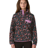 A woman wearing the Patagonia women's synchilla jacket in soft spirea dried vanilla available at Babipur. A green, brown and pink patterned fleece type jacket. Features the logo patch stitched on the left chest pocket, popper fasteners and a chest pocket. 