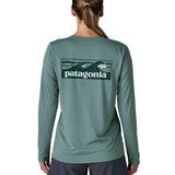 Woman wearing Patagonia's women's long sleeve capilene cool t-shirt in sage blue with wave logo graphic on upper back