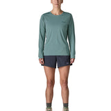 Woman wearing Patagonia's women's long sleeve capilene cool t-shirt in sage blue. T-shirt has a relaxed fit and sits at the hips