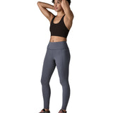 A female standing in front of a white background wearing a sports vest and the Patagonia women's activewear tights in dark blue with side pockets