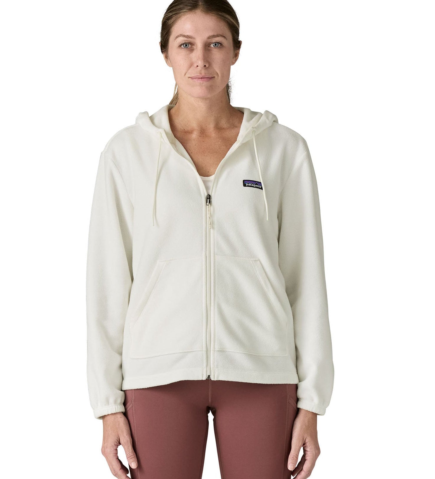 Woman wearing Patagonia's micro d hooded fleece in white. Fleece has a relaxed fit and sits at the hips