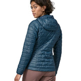 Back of Woman wearing the Patagonia nano puff hoody jacket in a lagom blue. Jacket has a regular fit and sits around the hips