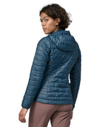 Back of Woman wearing the Patagonia nano puff hoody jacket in a lagom blue. Jacket has a regular fit and sits around the hips