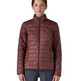 A female model wearing the Patagonia women's nano puff jacket in dark ruby showing the front fit of the jacket with a closed zip
