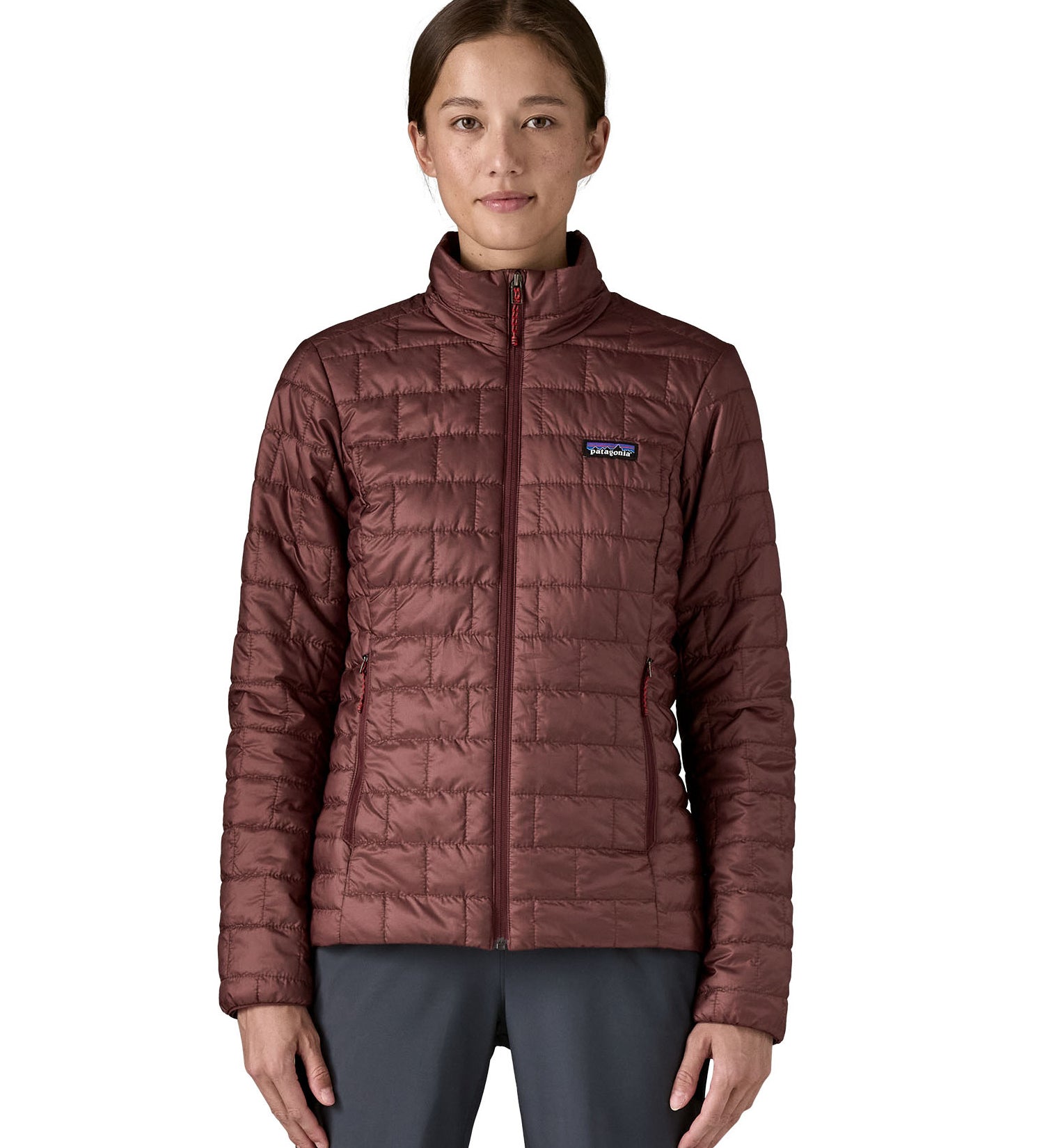 A female model wearing the Patagonia women's nano puff jacket in dark ruby showing the front fit of the jacket with a closed zip