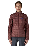 A female model wearing the Patagonia women's nano puff jacket in dark ruby showing the front fit of the jacket with a closed zip